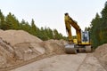 Excavator during construction new road in forest area. Backhoe at groundwork. Earth-moving equipment fort road work, grading, pool