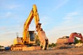 Excavator on a construction site cuts and crumbles old concrete and asphalt.