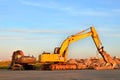 Excavator on a construction site cuts and crumbles old concrete and asphalt.