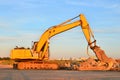 Excavator on a construction site cuts and crumbles old concrete and asphalt.