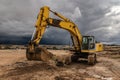 Excavator at a construction site surrounded by dramatic clouds