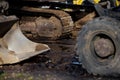 Excavator crawler track system and loader wheel in muddy construction site ground showing heavy machinery interaction and durable Royalty Free Stock Photo