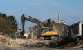 Excavator among debris and dust demolishes the old house for an urban redevelopment