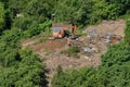 Excavator demolishes illegal buildings in the forest. Destroy of an illegally built old building in nature - Moscow, Russia, June