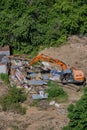 Excavator demolishes illegal buildings in the forest among green trees - Moscow, Russia, June 26, 2020
