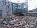 Excavator demolishing concrete and brick rubble