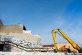 Excavator demolishing old building which walls with graffiti in day time