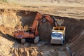 Excavator developing the sand in the opencast and loading it to the heavy dump truck. Processing of loose material in mining Royalty Free Stock Photo