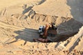 Excavator developing the sand on the opencast and loading it to the heavy dump truck. Processing of loose material in mining