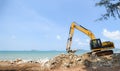 Excavator Digger Stone Working On Construction Site - Backhoe Loader On The Beach Sea Ocean And Blue Sky Background