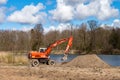 Excavator digging the ground. Construction equipment on the shore of the pond. Improvement of the shoreline Royalty Free Stock Photo