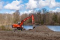 Excavator digging the ground. Construction equipment on the shore of the pond. Improvement of the shoreline Royalty Free Stock Photo