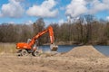 Excavator digging the ground. Construction equipment on the shore of the pond. Improvement of the shoreline Royalty Free Stock Photo