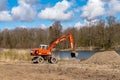 Excavator digging the ground. Construction equipment on the shore of the pond. Improvement of the shoreline Royalty Free Stock Photo