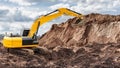 Excavator is digging into a large mound of earth at a construction site under a cloudy sky. The machine is actively moving soil Royalty Free Stock Photo