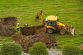 Excavator digs a hole to repair sewer pipes for sewage, workers control the process