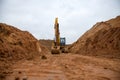 Excavator digs a large trench for pipe laying. Backhoe during earthmoving at construction site. Earth-moving heavy equipment Royalty Free Stock Photo