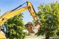 An excavator digs a pond pit in the garden against the blue sky. Digging a pit with an excavator. Earthmoving equipment and Royalty Free Stock Photo