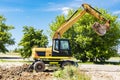 An excavator digs a pond pit in the garden against the blue sky. Digging a pit with an excavator. Earthmoving equipment and Royalty Free Stock Photo