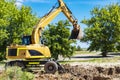 An excavator digs a pond pit in the garden against the blue sky. Digging a pit with an excavator. Earthmoving equipment and Royalty Free Stock Photo