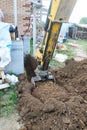 The excavator digs a small trench in the yard