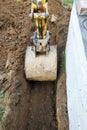 The excavator digs a small trench in the yard