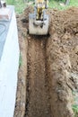 The excavator digs a small trench in the yard