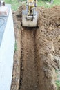 The excavator digs a small trench in the yard