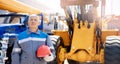 Excavator driver in hard hat stands at construction equipment, concept banner industrial man portrait Royalty Free Stock Photo