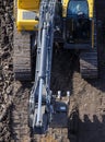 The excavator drives on the ground, leaving a tracked track. View from above.