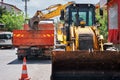 Excavator dumping soil to a dump truck at the road construction