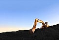 Excavator during earthmoving at coal open pit on sunset background. Construction machinery and earthworks heavy equipment for Royalty Free Stock Photo