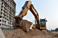 Excavator on earthmoving at construction site. Backhoe dig pit foundation. Construction machinery and equipment on groundwork.