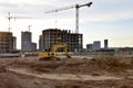 Excavator on earthmoving at construction site. Road work and Dig pit foundation. Tower cranes in action on blue sky background. Royalty Free Stock Photo