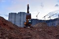 Excavator during earthmoving at construction site on sunset background. ÃÂ¡onstruction machinery for excavating. Tower cranes