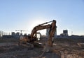 Excavator on earthworks at construction site. Backhoe on foundation work and road construction. Tower cranes in action on blue sky Royalty Free Stock Photo