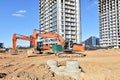 Excavator on earthworks at construction site. Backhoe on foundation work and road construction. Tower cranes in action on blue sky Royalty Free Stock Photo