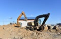 Excavator on earthworks at construction site. Backhoe on foundation work and road construction. Tower cranes in action on blue sky Royalty Free Stock Photo