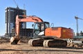 Excavator on earthworks at construction site. Backhoe on foundation work and road construction. Tower cranes in action on blue sky Royalty Free Stock Photo