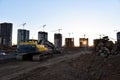 Excavator on earthworks at construction site. Backhoe on foundation work and road construction. Tower cranes in action on blue sky Royalty Free Stock Photo