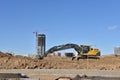 Excavator on earthworks at construction site. Backhoe on foundation work and road construction. Tower cranes in action on blue sky Royalty Free Stock Photo