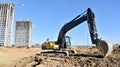 Excavator on earthworks at construction site. Backhoe on foundation work and road construction. Tower cranes in action on blue sky Royalty Free Stock Photo