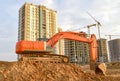 Excavator during excavation aond road construction works at construction site on sunset background. Backhoe on foundation work in Royalty Free Stock Photo