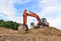 Excavator during excavation aond road construction works at construction site on sunset background. Backhoe on foundation work in Royalty Free Stock Photo