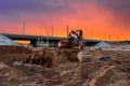 Excavator during excavation at construction site on amazing sunset background. Backhoe on road work. Heavy Construction Equipment Royalty Free Stock Photo