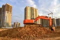 Excavator during excavation at construction site on sunset background. Red Backhoe on road work. Heavy Construction Equipment for Royalty Free Stock Photo