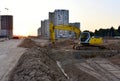 Excavator during excavation at construction site on sunset background. Red Backhoe on road work. Heavy Construction Equipment for Royalty Free Stock Photo