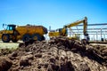 Backhoe is loading a truck with ground on building site