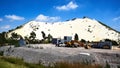 Excavator in front of white overburden