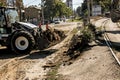 Excavator, grader and workers remove debris after dismantling a tram stop. Works on tram tracks